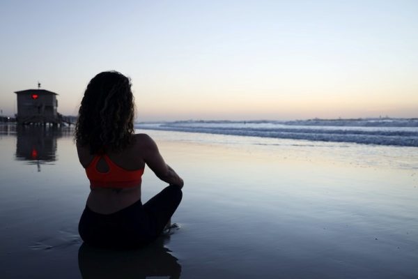 women meditating on a sandy beach